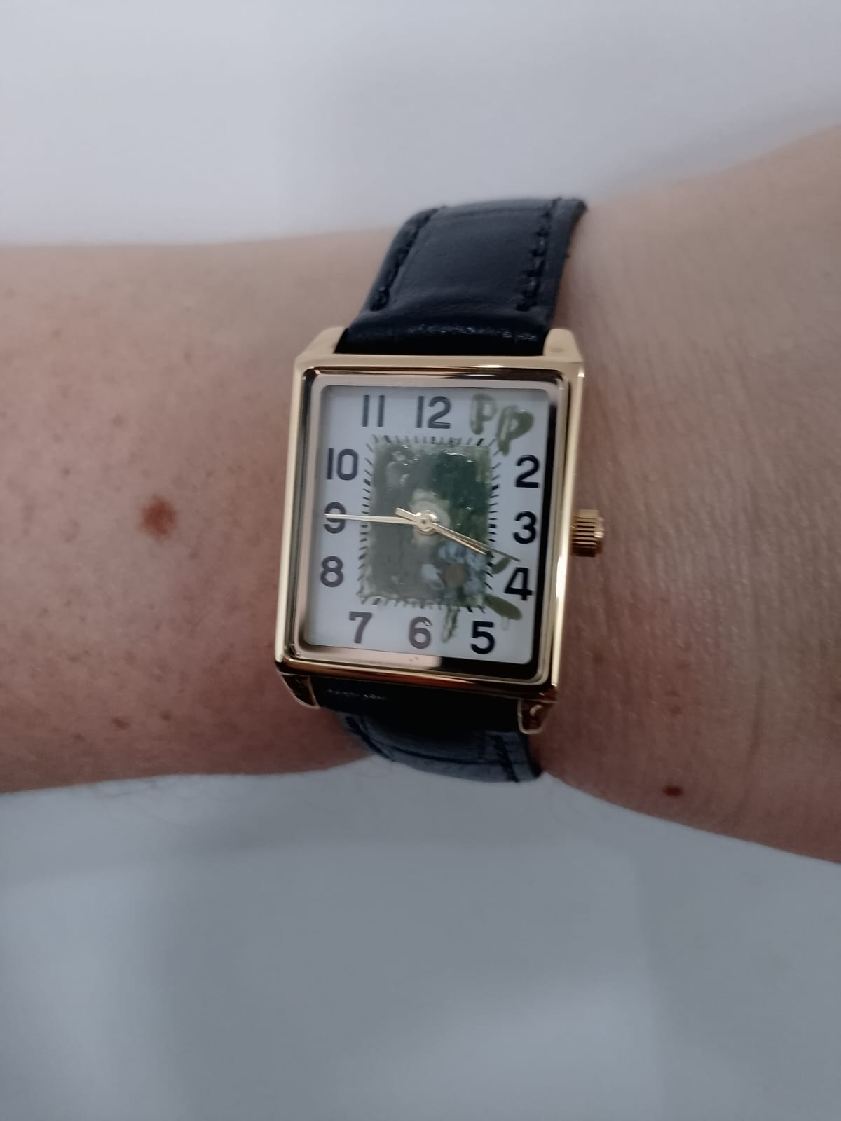 PP Atelier Arte no pulso, com caixa Tank dourada, mostrador pintado à mão em verde oliva com motivo floral e pulseira preta de couro genuíno.
